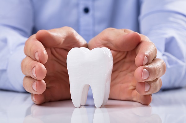 Man's,Hand,Protecting,Healthy,Hygienic,White,Tooth,On,Reflective,Table